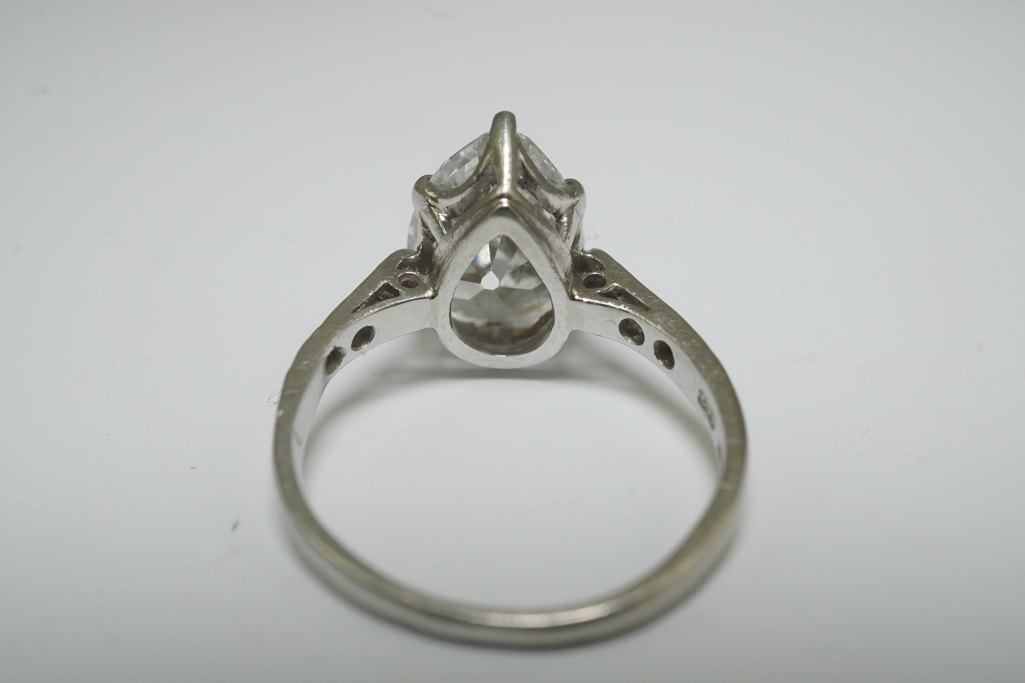 A platinum and pear cut single stone diamond set ring, with diamond set shoulders